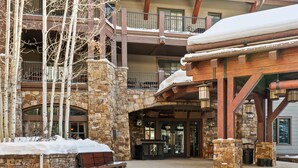 A multi-story building with stone and wood architecture, featuring balconies and a covered entrance. - The Ritz-Carlton Club | Two-Bedroom Residence 8412, Ski-in & Ski-out Resort in Aspen Highlands (Aspen)