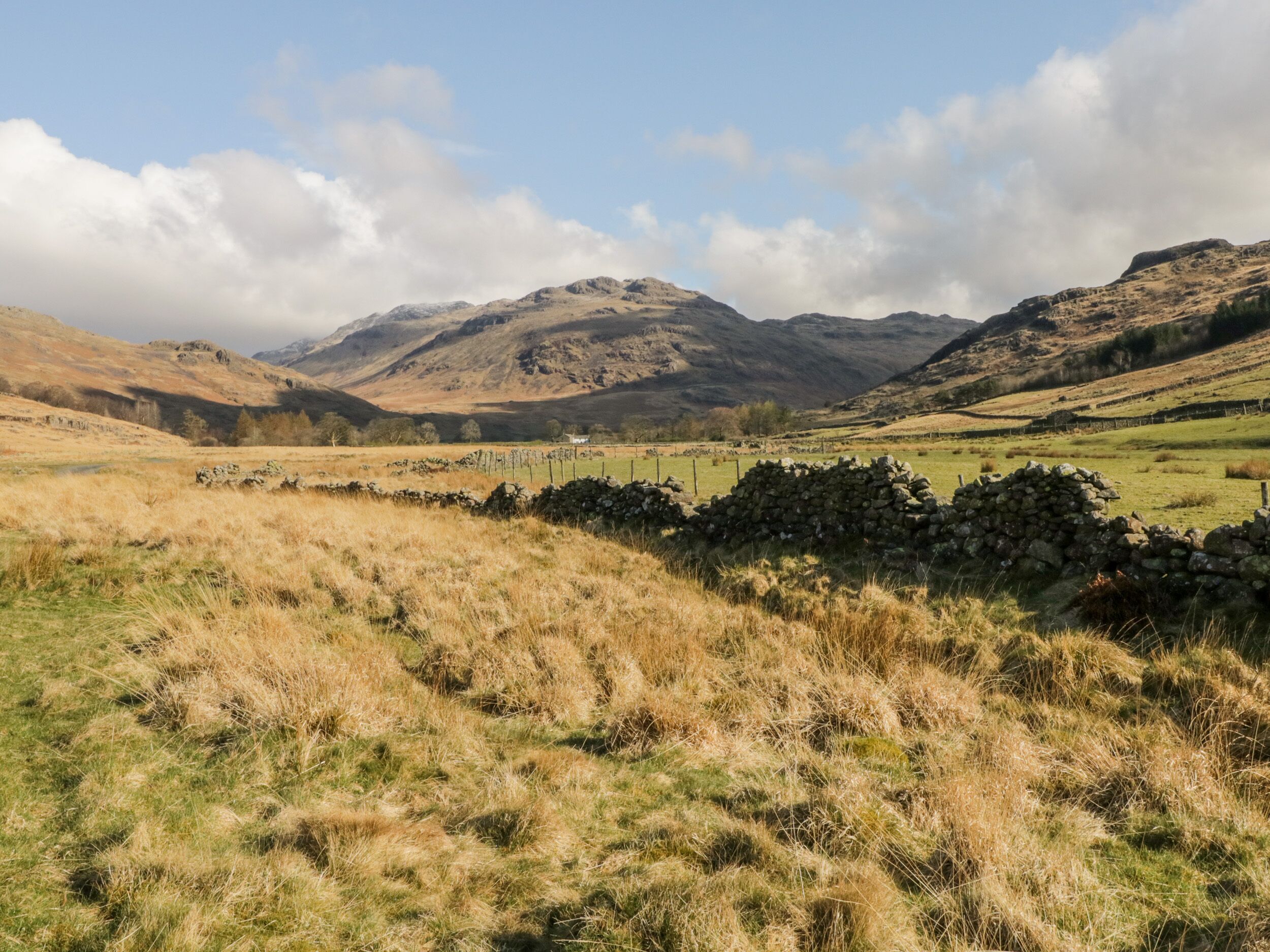 A rural landscape with rolling hills, stone walls, and a clear sky.