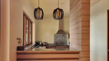 A kitchen with a stone countertop, hanging pendant lights, and a built-in stove.