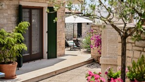 A stone building with a door, a small patio with a table and chairs, and potted plants.