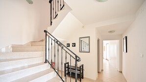 A staircase with a black railing leading to a landing area with a small table and chairs.