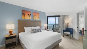 A hotel room with a large bed, two nightstands, a chair, and a view of the ocean. - Newly Renovated Ocean View 2BR Condo on 11th Floor (Myrtle Beach)