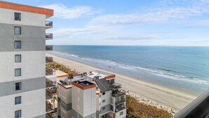 A high-rise hotel with balconies overlooking a beach.
