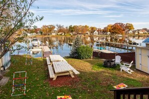 A lakeside backyard with a dock, picnic table, and outdoor seating. - Serenity on the Cove (Dundalk)
