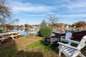 A lakeside view with a dock, boats, and a picnic area with chairs and a grill. - Serenity on the Cove (Dundalk)