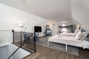 A modern apartment with a loft-style bedroom, a living area with a sofa and TV, and a staircase with a railing. - Serenity on the Cove (Dundalk)
