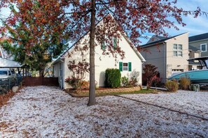 A single-story house with a white exterior, green shutters, and a gravel driveway. - Serenity on the Cove (Dundalk)