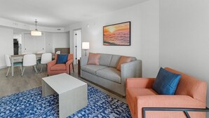 A modern living room with a sofa, armchairs, a coffee table, and a dining area with chairs and a table.