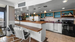 A modern kitchen with white cabinetry, a wooden island, and pendant lighting. - Oceanfront 1BR Penthouse with Breathtaking Views (Myrtle Beach)