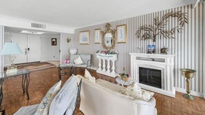 A living room with a fireplace, a sofa, a coffee table, and a decorative mirror. - Oceanfront 1BR Penthouse with Breathtaking Views (Myrtle Beach)