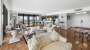 A spacious living area with a large sofa, a dining table, and a kitchen in the background. - Oceanfront 1BR Penthouse with Breathtaking Views (Myrtle Beach)