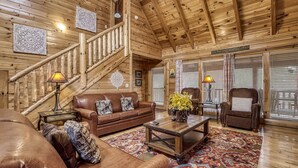 A wooden interior with a staircase, leather furniture, and a patterned rug. - Spacious 4BR Cabin w/ Game Room, Hot Tub & Pools – 3 Miles to Parkway (Sevierville)