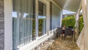 A covered patio with a table and chairs, large windows, and a stone wall. - Mobile Homes with Shared Pool Rocco 2 (Medulin)