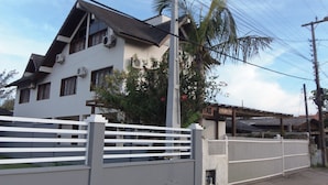 Ein modernes, zweistöckiges Haus mit weißer Fassade, zahlreichen Fenstern und einem umzäunten Garten.