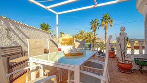 A patio with a glass table and white chairs, surrounded by potted plants and palm trees. - Awesome home in Ciudad Quesada (Ciudad Quesada)