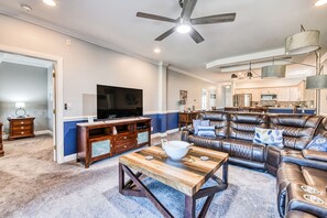 A spacious living room with a leather sofa, a wooden coffee table, and a television.