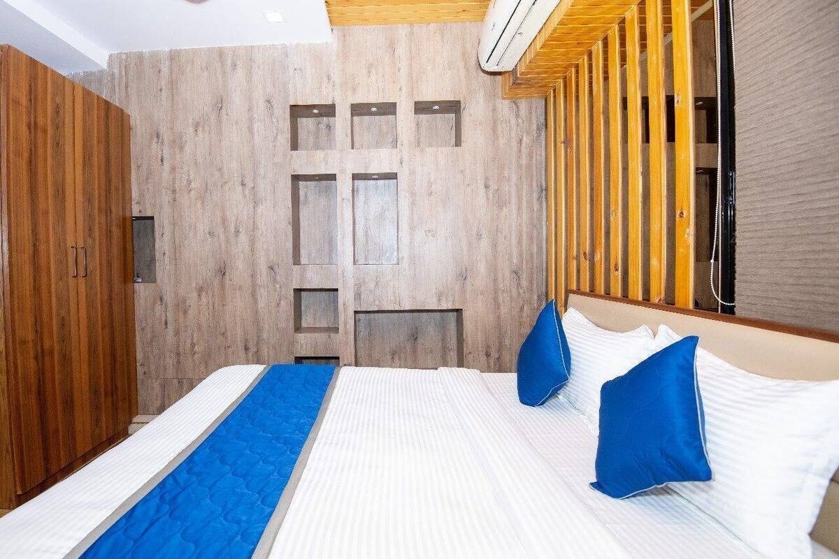 A hotel room with a large bed, wooden wardrobe, and a modern design.