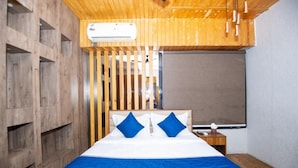 Una habitación con una cama, un panel de pared de listones de madera, una ventana y un equipo de aire acondicionado.