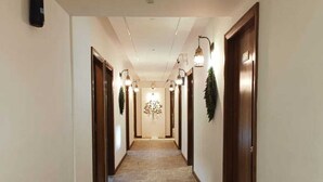 Un pasillo de hotel con piso de baldosas, puertas de madera e iluminación empotrada en la pared.