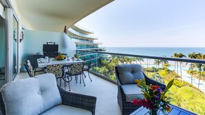 A balcony with a dining area, a grill, and a view of the ocean. - NEW Beach Club Game Room Cinema Condos (Nuevo Nayarit)