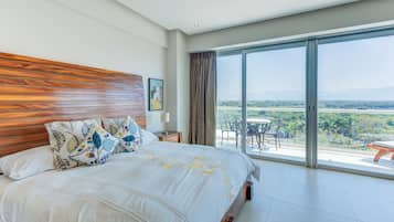 Un dormitorio amplio con una cama grande, un cabecero de madera y un balcón con vistas al paisaje.