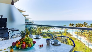A balcony with a table set for breakfast, overlooking a beach and ocean view. - NEW Beach Club Game Room Cinema Condos (Nuevo Nayarit)