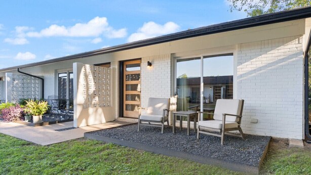 Une maison moderne dotée d’un patio comprenant un espace salon extérieur et une grande porte-fenêtre coulissante.