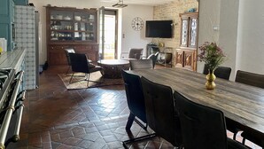 Una cocina amplia con comedor, que incluye una gran mesa de madera, sillas y piso de baldosas de piedra.