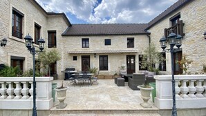 Un edificio de piedra con un patio amoblado y una parrilla.