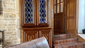 Un gabinete de madera con puertas de cristal, un sillón de cuero y una escalera que lleva a una puerta de madera.