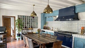 Una cocina con una mesa de madera, armarios azules y salpicadero de azulejos.