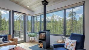 A modern living room with large windows, a fireplace, and a cozy seating area.