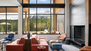 Ein modernes Wohnzimmer mit großem Fenster und Bergblick, inklusive Kamin und zeitgemäßer Einrichtung.
