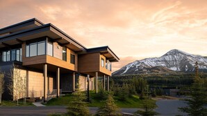Ein modernes, zweistöckiges Haus mit großen Fenstern und Blick auf die Berge.