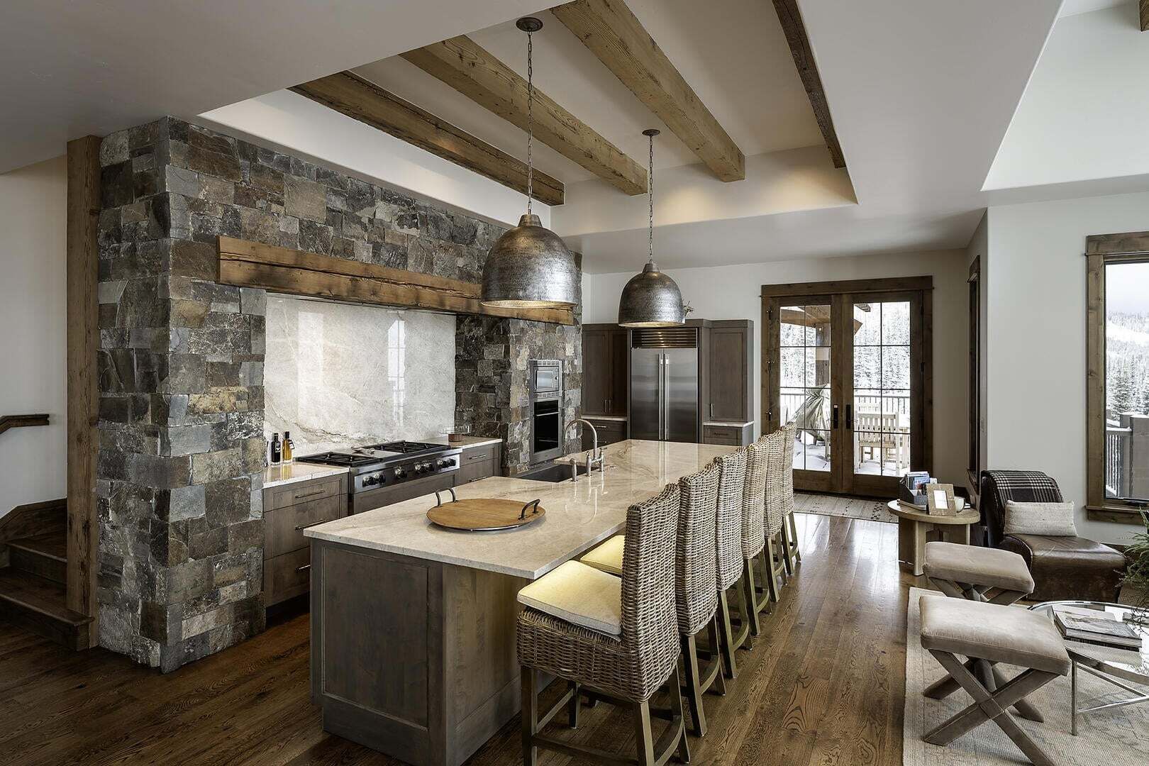 A modern kitchen with a stone accent wall, a large island, and a dining area with wicker chairs.