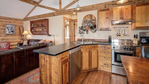 A rustic kitchen with wooden cabinets, a central island, and a dining area.