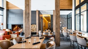Un restaurante moderno con pilares de madera, chimenea y una zona de estar acogedora.