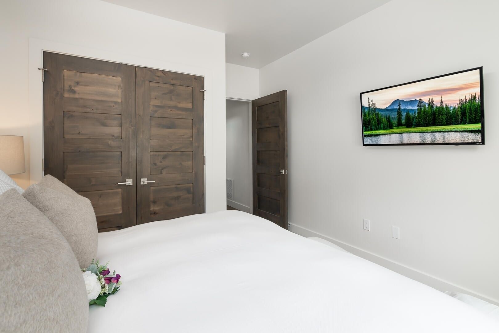 Un dormitorio con una cama grande, dos puertas de madera y un cuadro enmarcado en la pared.