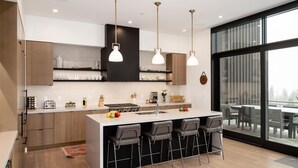 Une cuisine moderne dotée d’un îlot central, de tabourets de bar et de luminaires suspendus.