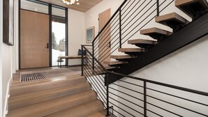 Un escalier moderne avec des marches en bois et une rampe noire, menant à l’étage supérieur.