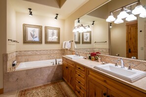 Relax in a spacious bathroom with a bathtub, double vanity, and large mirror.
