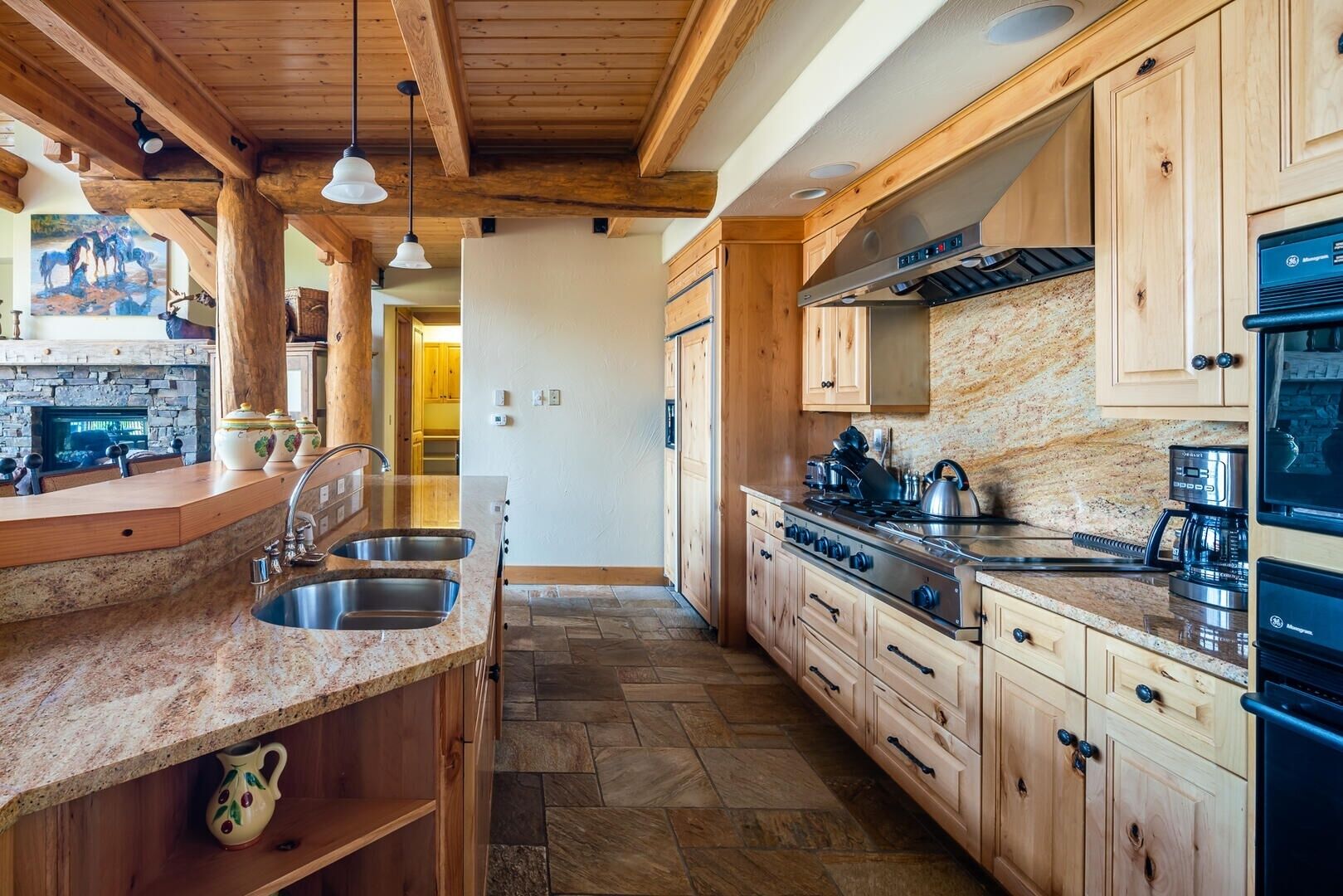 A modern kitchen with granite countertops, wooden cabinets, and a central island with a sink.