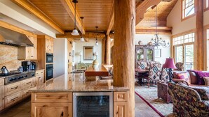 A spacious kitchen with wooden cabinets and a central island, a dining area with patterned furniture, and a cozy living room with a fireplace.