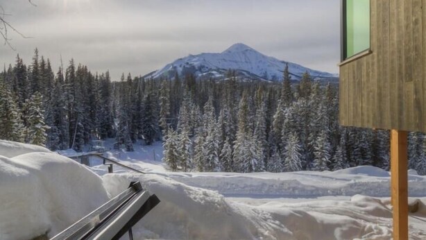 A hot tub with a view of a snowy mountain and forest. - 17 Lake Cabin 3 Bedroom Home by Moonlight Basin Lodging (Big Sky)