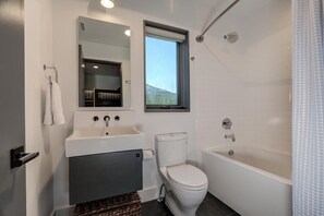 A modern bathroom with a toilet, sink, and bathtub.
