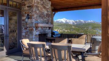 Un patio exterior con muros de piedra, una chimenea de piedra y vistas a montañas nevadas.
