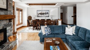 A spacious living room with a large blue sofa, a fireplace, and a dining area with wooden furniture.