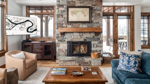 A cozy living room with a stone fireplace, a map on the wall, and a blue sofa.
