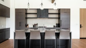 A modern kitchen with a central island, four bar stools, and pendant lighting. - 212 Lakelodge 3 Bedroom Condo by Moonlight Basin Lodging (Big Sky)