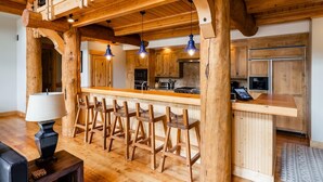 Une cuisine rustique avec des poutres en bois, un coin bar avec des tabourets et des appareils électroménagers modernes.